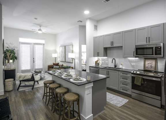 a kitchen and living room with a large island with stools