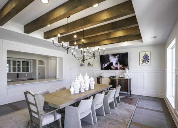 a dining room with a long wooden table and white chairs