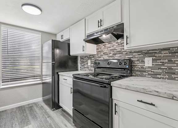 A kitchen with black appliances and white cabinets.