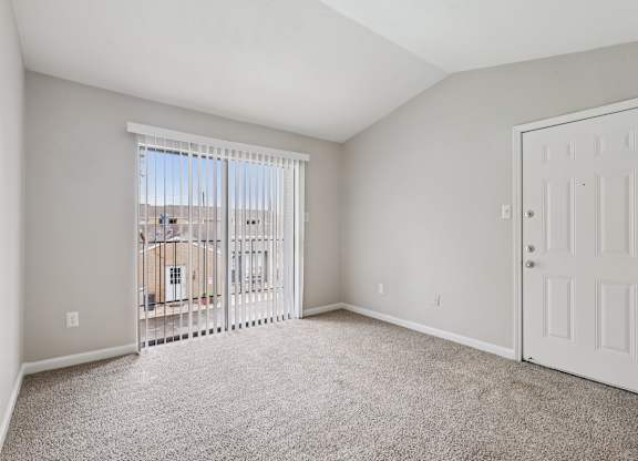 A room with a white door and a window with a view of a building outside.