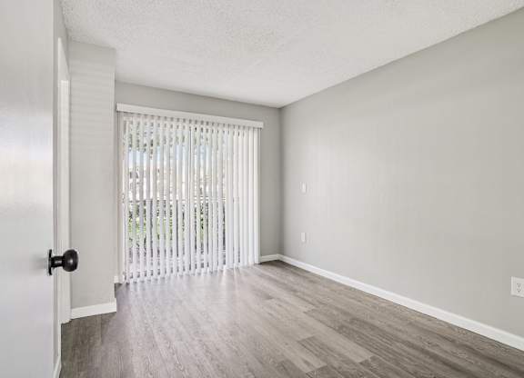 A room with a door and a window with blinds.