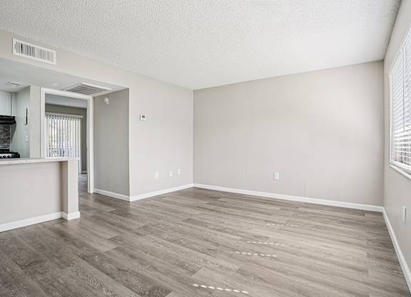 A room with a wooden floor and a window with blinds.