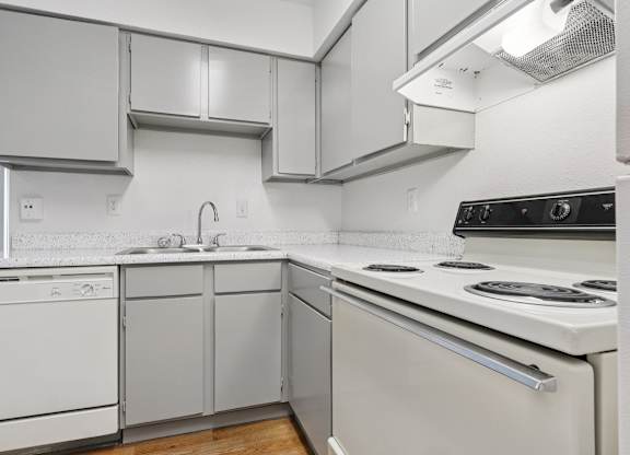 A white kitchen with a stove top oven and a dishwasher.