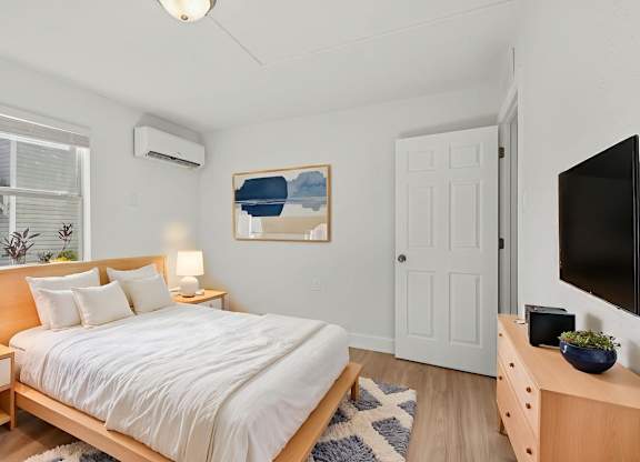 A bedroom with a bed, nightstands, and a painting on the wall.