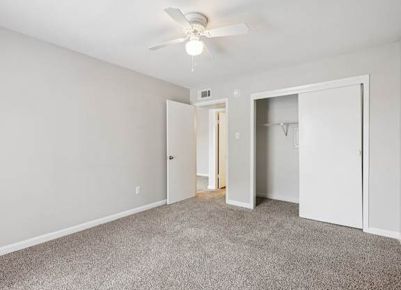 A room with a ceiling fan and carpeted floor.