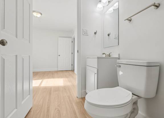 A white toilet in a small bathroom with a sink and mirror.
