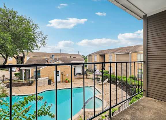 A pool in a backyard with a fence and houses in the background.