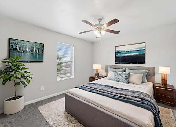 A bedroom with a large bed and a ceiling fan.