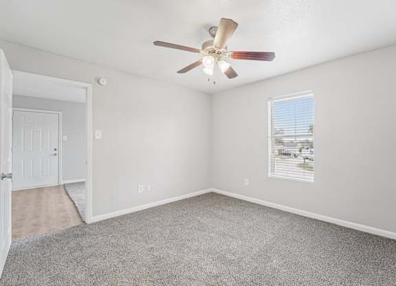 A room with a ceiling fan and a window with blinds.