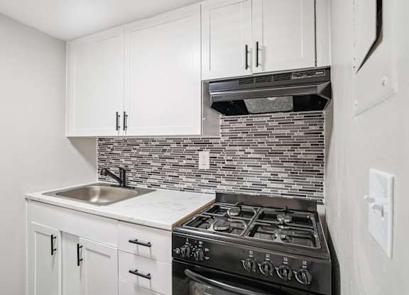A kitchen with a black stove top oven and white cabinets.