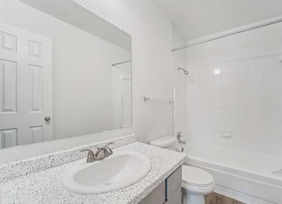 A white bathroom with a sink, toilet, and bathtub.