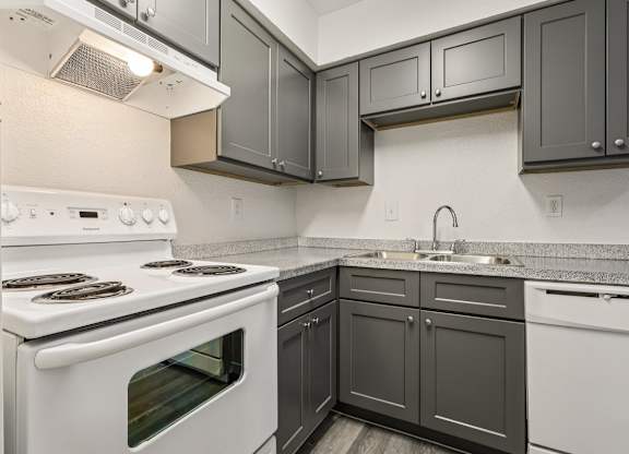 A kitchen with a white stove and black cabinets.