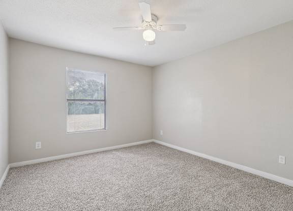 A room with a ceiling fan and carpeted floor.