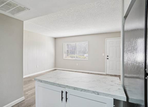 A kitchen with a marble countertop and white cabinets.