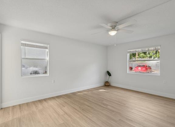 A room with a ceiling fan and two pictures on the wall.