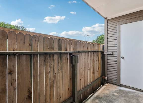 A wooden fence with a white door and a grey wall.
