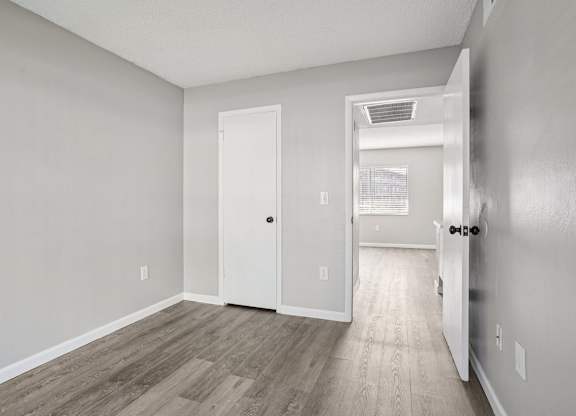 A room with a white door and a wooden floor.
