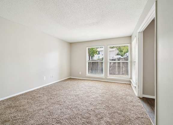 A room with a carpeted floor and a window with blinds.