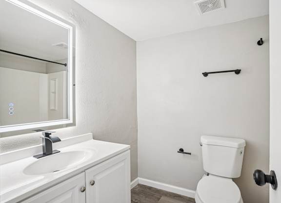 A white bathroom with a toilet, sink, and mirror.