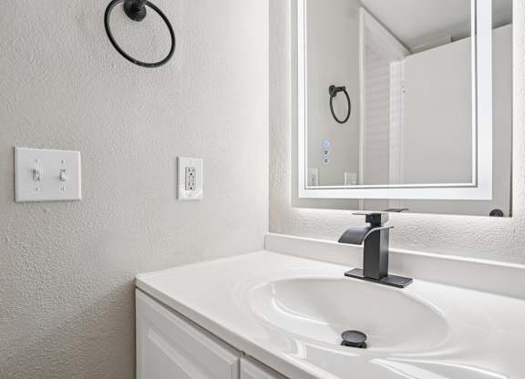 A white sink in a bathroom with a mirror above it.