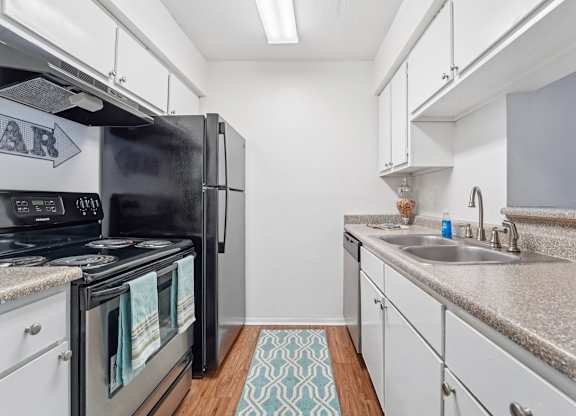 A kitchen with a black refrigerator and white cabinets.