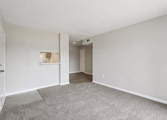 A spacious room with a carpeted floor and white walls.