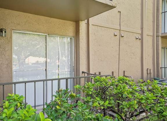 A balcony with a metal railing and bushes in front.