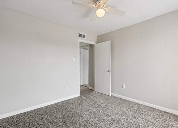 A room with a ceiling fan and carpeted floor.