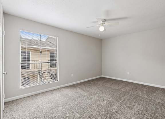A room with a carpeted floor and a ceiling fan.