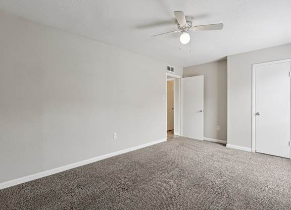 A room with a ceiling fan and carpeted floor.