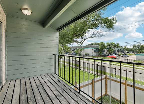 A balcony with a black railing and wooden floor.