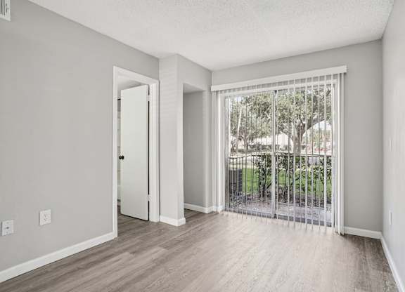 A room with a sliding glass door leading to a backyard.