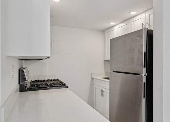 A kitchen with a stainless steel refrigerator and a white countertop.