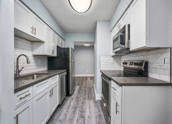 an empty kitchen with white cabinets and a black stove and refrigerator at Ascot Place Apartments, Birmingham, AL