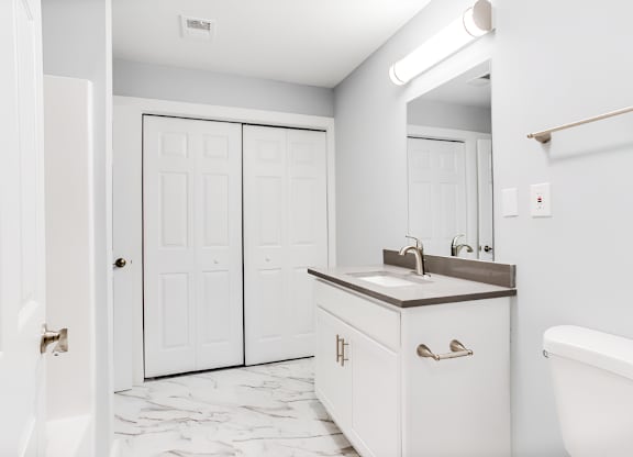a bathroom with white cabinets and a sink and a mirror at Ascot Place Apartments, Birmingham, 35235 