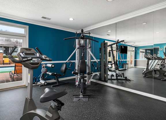a gym with weights and cardio equipment in a home with blue walls and a window at Ascot Place Apartments, Birmingham Alabama