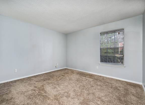 an empty room with carpet and a window at Ascot Place Apartments, Birmingham, AL
