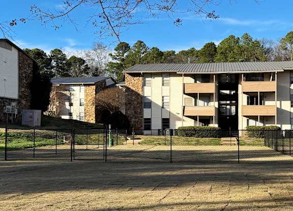 Apartment complex with a fenced parking lot in front.