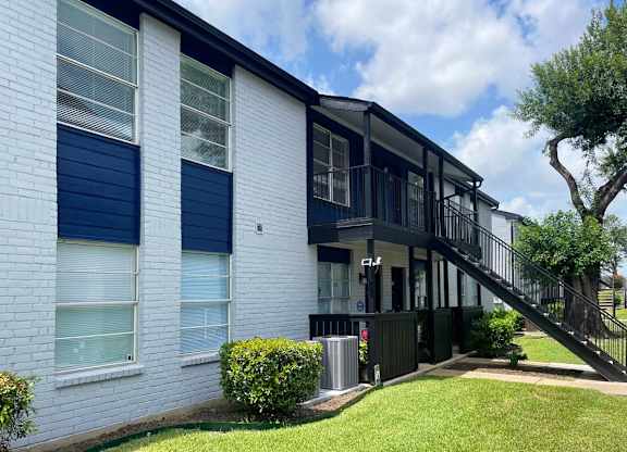 A white house with blue shutters and a black railing.