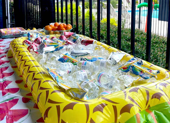 A table covered with a yellow tablecloth and filled with plastic bottles.