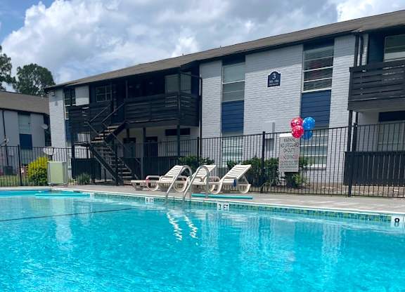 A pool with chairs and a balloon in front of a building.