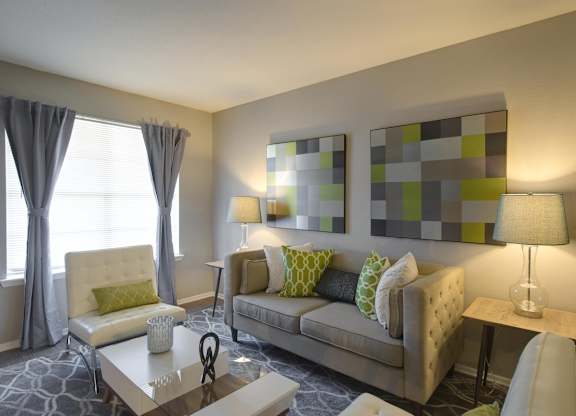 a living room with a couch, large windows, and model decor