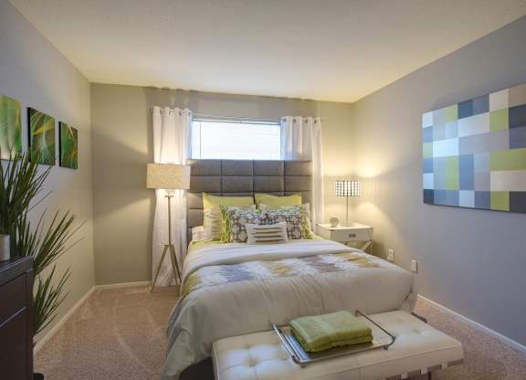 a bedroom with plush carpeting, a window, neutral paint, and model furnishings