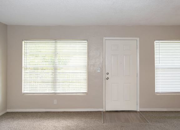 a spacious living room with large windows, a door