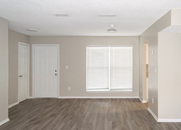 an empty living room with a large window and wooden floors