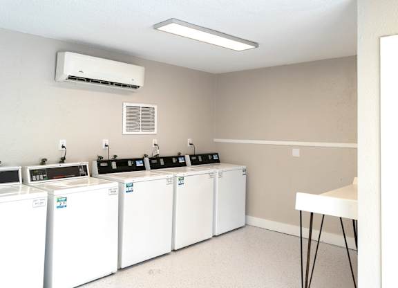 a group of washers and dryers in a room with a table and a