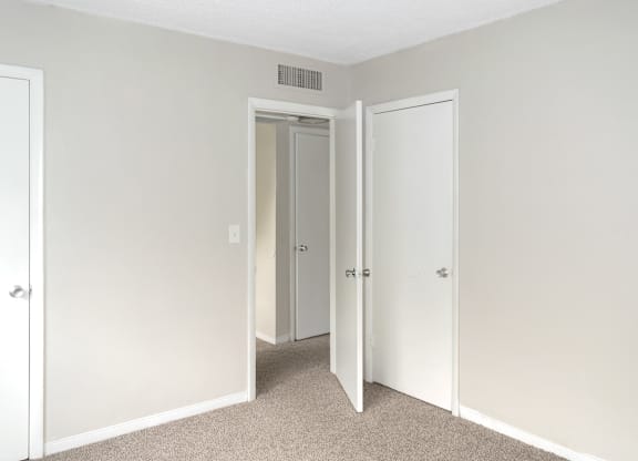 A bedroom with a carpeted floor and three doors.