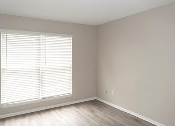 a bedroom with large windows, wood-style flooring, and neutral paint colors