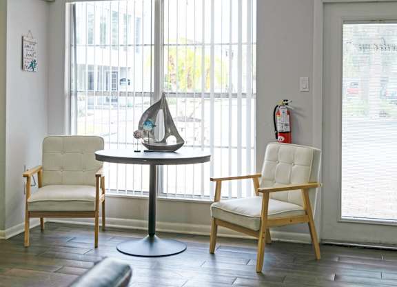 a living room with two chairs and a table and a window