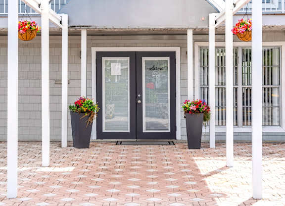 the front door of a house with flowers on the pillars